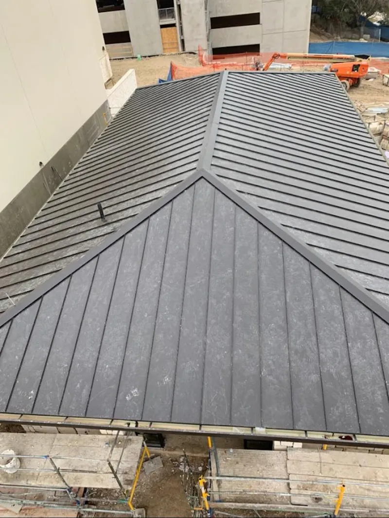 Commercial metal roof construction with crane equipment in Metairie